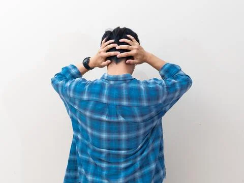 Back view of a stressed young Asian man wearing a plaid shirt and holding h.. Stock Photos
