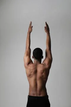 Back view of strong athletic black man shows naked muscular body. Vertical. Stockfoto's