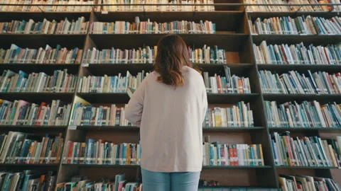 Back view of a student looking at rows of bookshelves Stock Footage 211417844