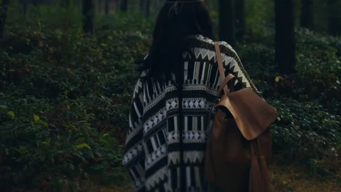 Back view of stylish attractive hippie girl walking through the dark forest 스톡 동영상 108731645