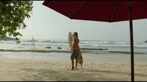 Back view of surfer with disability standing next to ocean. Long shot of athlete Stock Footage 192435313