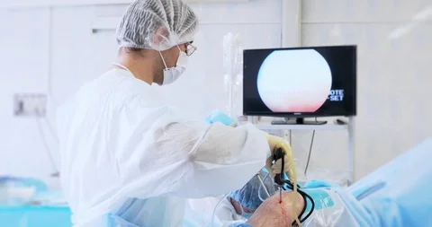 Back view of surgeon looking at monitors while preforming operation using Stock Footage 121104283