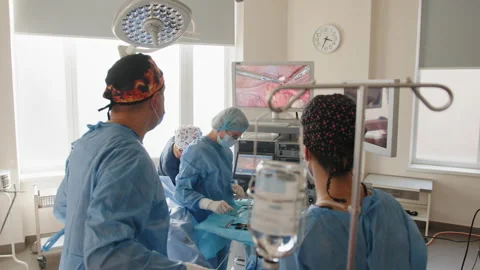 Back view of surgeons team looks at monitors while preforming operation in Stock Footage 174230570