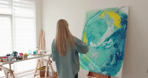 Back view of talented female painter with long blond hair standing at art studio Vídeo Stock 154811325
