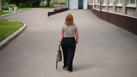 Back View of Teacher Walking Toward School Building Holding Handbag Vídeos de archivo 326046015