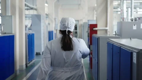 Back view of a technician in a white lab coat walking through a sterile Vídeos de archivo 325976909