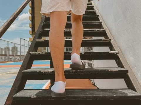 Back view of Thai man walking upstairs wearing casual outfit and white shoe.. Stock-Fotos