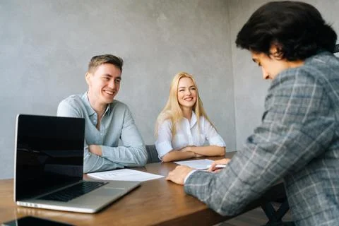 Back view of three cheerful young colleagues conducting business presentation Stock Photos