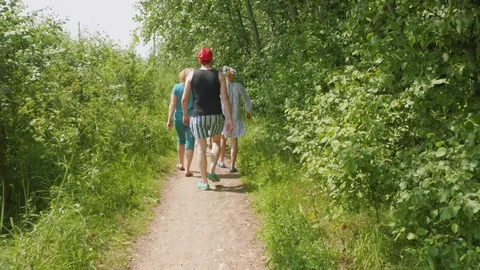 Back view of three people walking on country road on summer afternoon 스톡 동영상 94564623