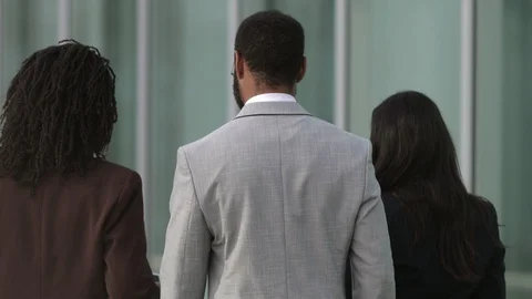 Back view of three people wearing suits walking near building Stock Footage 114964936