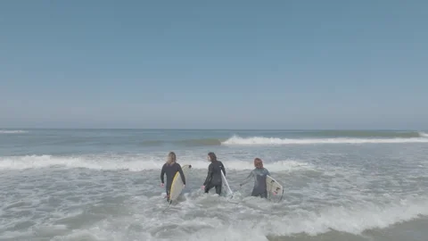Back view three surfers entering sea Stock Footage 345225956