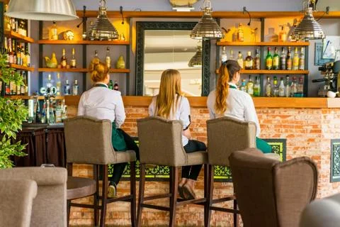 Back view of three waitresses sitting on chairs Stock Photos