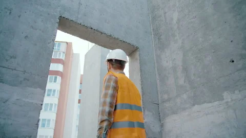 Back view of tired builder looking out of window at construction site Video stock 247765539