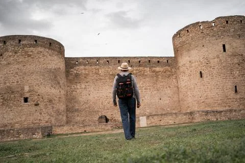 Back view of tourist in hat walking to ancient Akkerman fortress traveler tra Stock Photos
