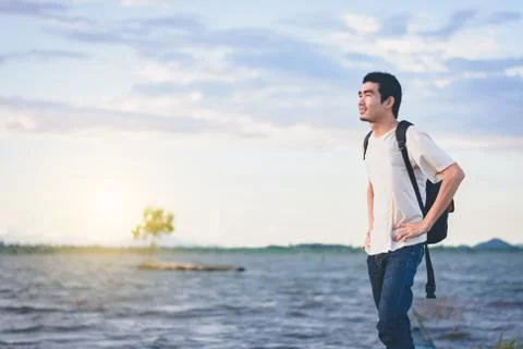 Back view of Travel man with backpack standing on tail of the boat with lake Stock Photos