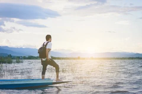 Back view of Travel man with backpack standing on tail of the boat with lake Stockfoto's