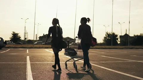 Back view of two attractive stylish girls walking on parking lot of shopping Stock Footage 80177440