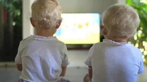 Back view of two blonde toddlers watching something on a big flat screen Stock Footage 150879049