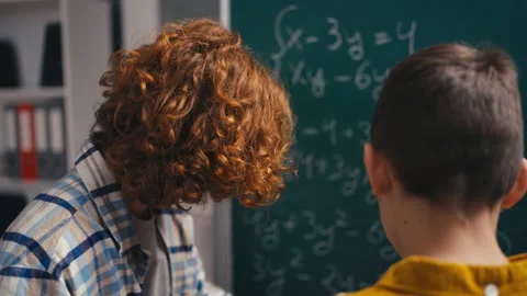 Back view of two boys trying to solve math task on chalkboard, algebra lesson Stock Footage 250334268