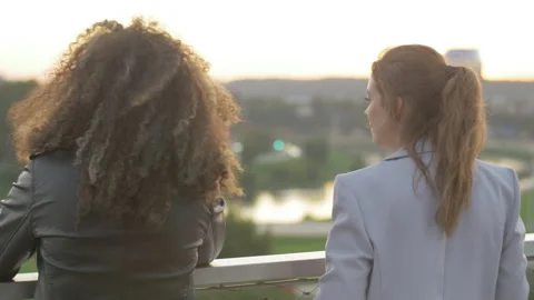 Back view of two close friends watching cityscape at sunset on rooftop Stock Footage 133157172