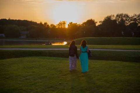 Back view of two friends walking together in a park at sunrise Stock Photos