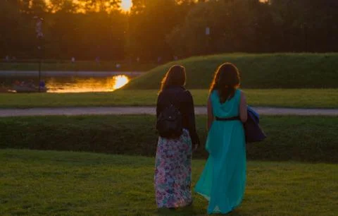 Back view of two friends walking together in a park at sunrise Stock Photos