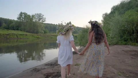 Back view at two girls walking in field holding hands at sunset outdoors Stock Footage 205440285