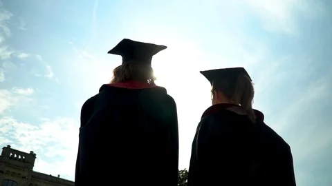 Back view of two happy joyful students in mantles celebrating their graduation Stock Footage 115651586