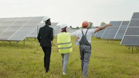 Back view of two inspectors in white helmets walking on solar station with Video stock 168496144