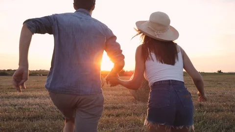 Back view of Two Loving People Running on the Harvested Field.  Видео 93842502