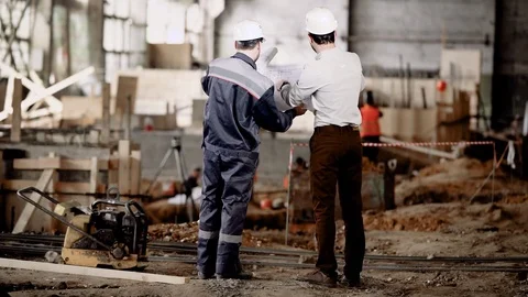 Back view of two men standing together in construction area and looking at shop Stock Footage 77626782