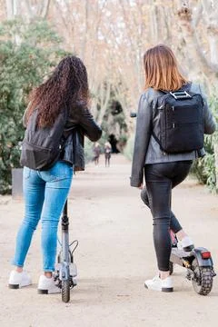 Back view of two multiethnic female friends on electric scooter. Urban lifestyle Foto stock