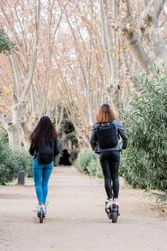 Back view of two multiethnic female friends on electric scooter. Urban lifestyle Stock Photos