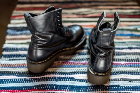Back view of two robust, black ankle leather boots on a colorful rug as a Stock Photos