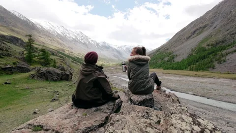 Back view of two travelers sit on a top of a rock Stock Footage 140497436