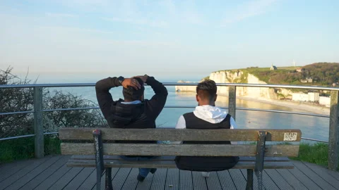 Back view of two unrecognizable men sitting relaxing on bench looking to famous Stock Footage 242185921