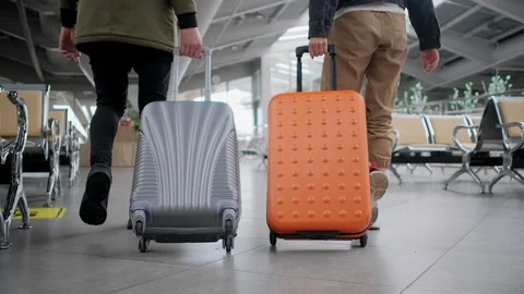 Back view of two walking people with rolling suitcase in airport hall Stock Footage 108059709