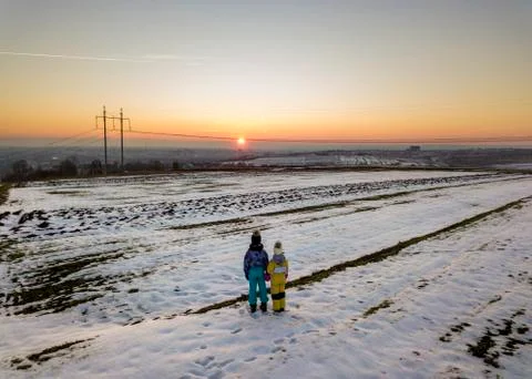 Back view of two young children in warm clothing standing in frozen snow fiel Stock Photos