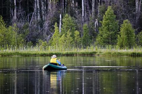 Back view of an unknown man fly-fishing using a float tube Foto stock