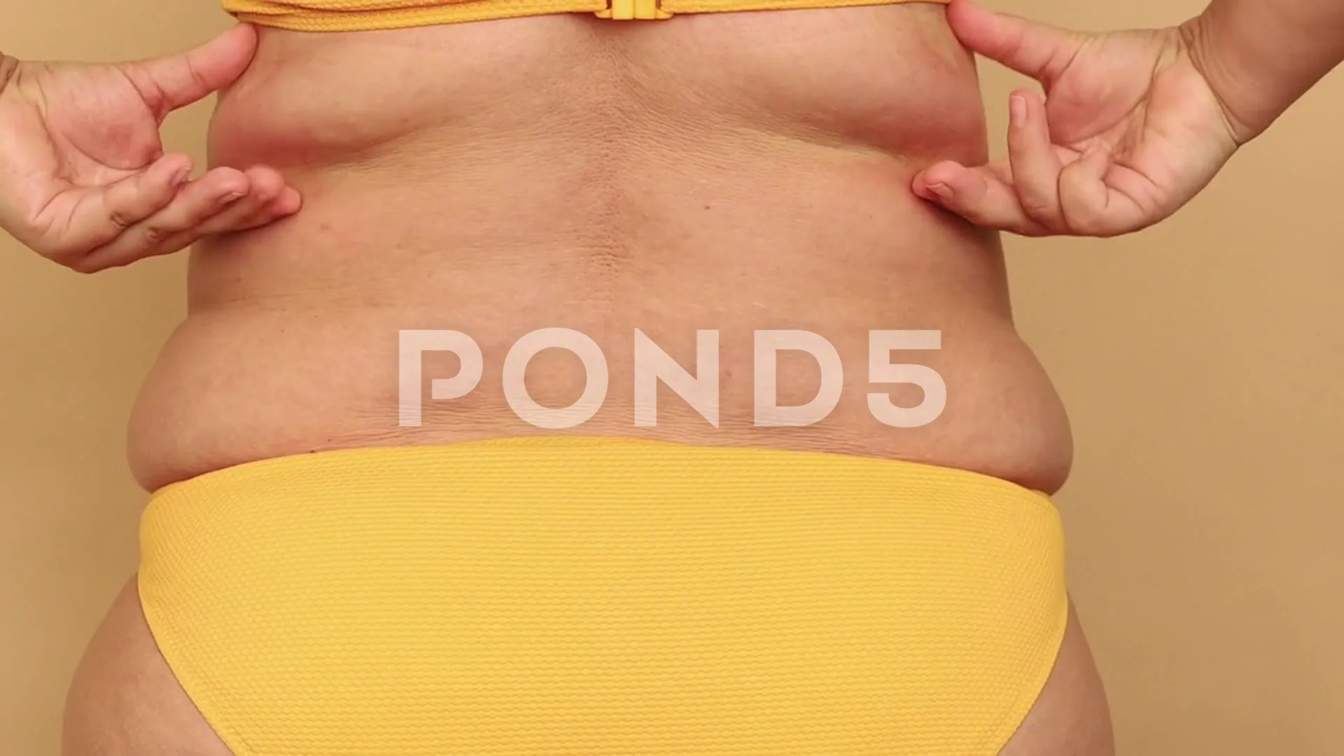 Back view of unrecognizable fat overweight woman wearing yellow bikini