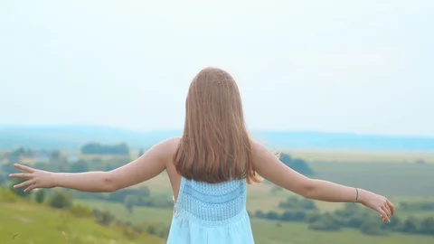 Back view of unrecognizable female standing on high hill raising her hands up to Stock Footage 113045412