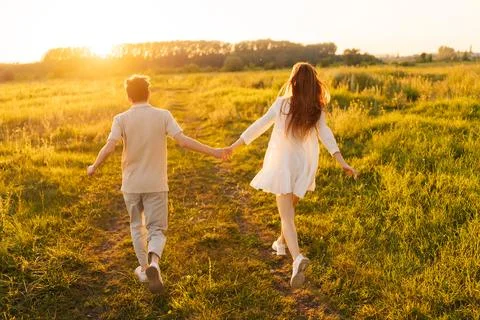 Back view of unrecognizable happy young couple in love taking each other hand Stock Photos