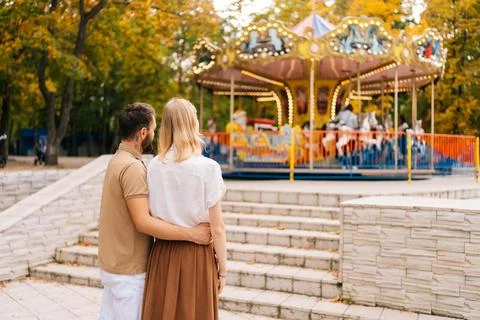 Back view of unrecognizable loving young couple standing hugging watching Stock Photos
