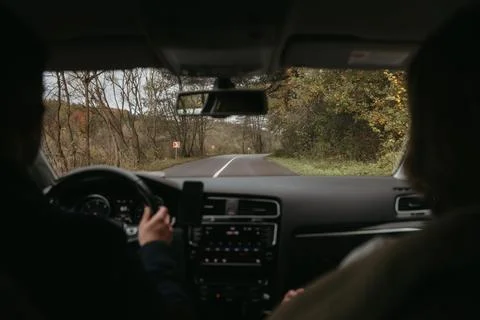 Back view of unrecognizable man and a woman driving car on a country road 库存照片