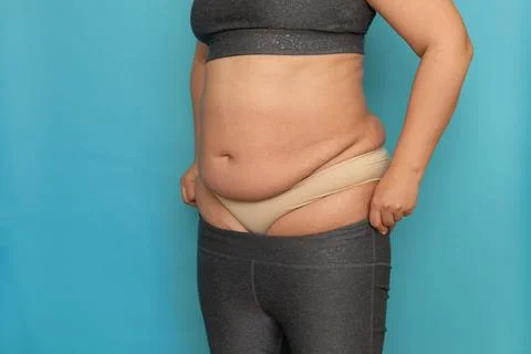 Back view of unrecognizable plump plus-size woman in grey sports bra, beige Stock Photos