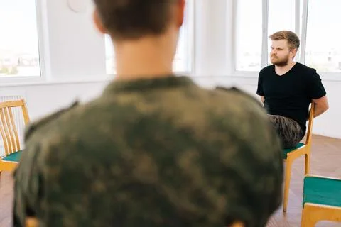 Back view of unrecognizable psychologist talking to group of male veterans in Stock Photos