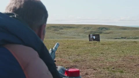 Back view of unrecognizable shooter shooting into target. Gun calibrating before Stock Footage 166107472