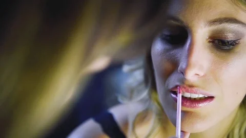 Back view of visagiste applying lipstick on young girl lips. Stock Footage 74730543
