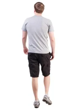 Back view of walking handsome man in shorts and sneakers Stock Photos