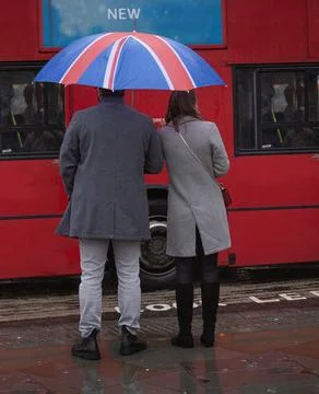 Back view of well-dressed young couple with British flag umbrella Stock Photos
